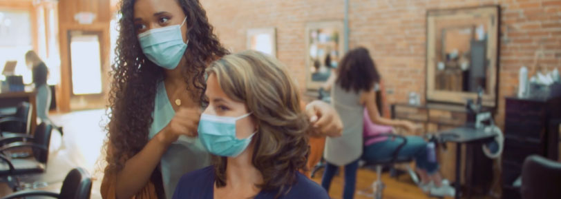 Hair stylist in mask speaks with customer in mask